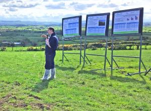 Scientist presenting in front of posters displayed in a field